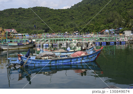 Fishing village with fishing boats and decorated pier in a sea bay in Vietnam next to the mountains Fishing village with fishing boats and decorated pier in a sea bay in Vietnam next to the mountains 130849074