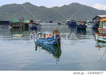 Fishing village with fishing boats and sheds in the sea bay near the mountains in Vietnam Fishing village with fishing boats and sheds in the sea bay near the mountains in Vietnam 130849077