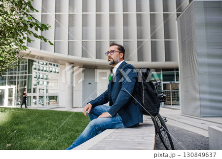 Business commuter taking a break with smartphone and bicycle in urban park. Business commuter taking a break with smartphone and bicycle in urban park. 130849637