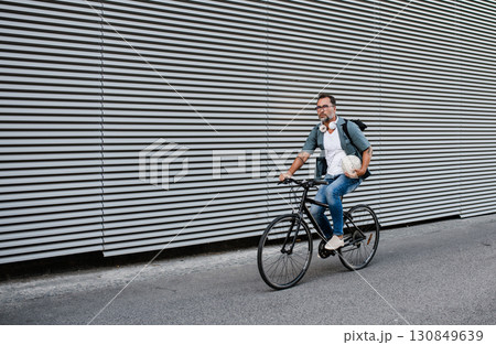 City commuter riding bike on street, wearing backpack. City commuter riding bike on street, wearing backpack. 130849639