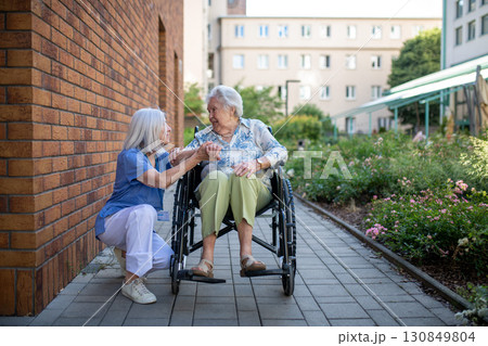 Senior patient in wheelchair talking with her caregiver. Senior patient in wheelchair talking with her caregiver. 130849804