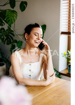 Confident woman sitting on sofa and making phone call. 130849835