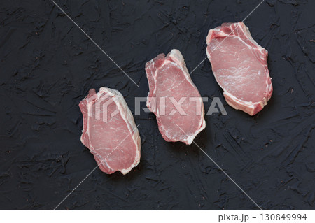 Raw Pork Chops with Spices and Herbs on Dark Rustic Background Raw Pork Chops with Spices and Herbs on Dark Rustic Background 130849994