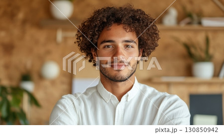 Smiling professional man with curly hair standing in office interior Smiling professional man with curly hair standing in office interior 130850942