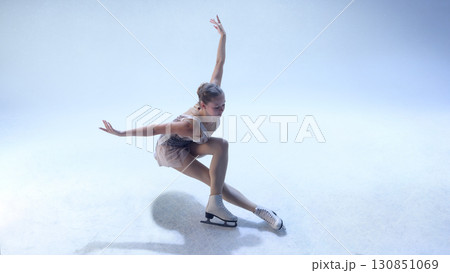 Figure skater bending low in dynamic choreographic move on white ice 130851069