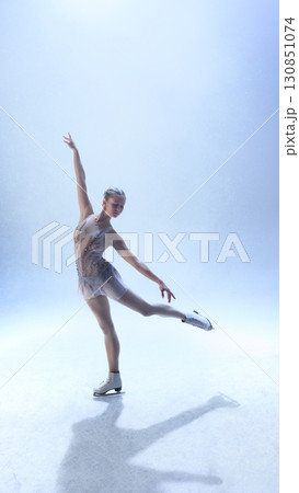 Female skater balancing with extended leg in soft white illuminated arena 130851074