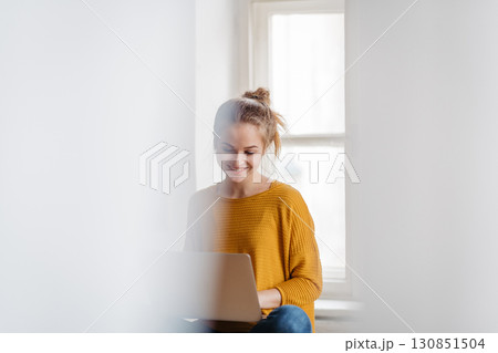 Young female student sitting at the table and studying. 130851504