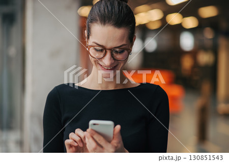 Portrait of young businesswoman reading email on smartphone. 130851543