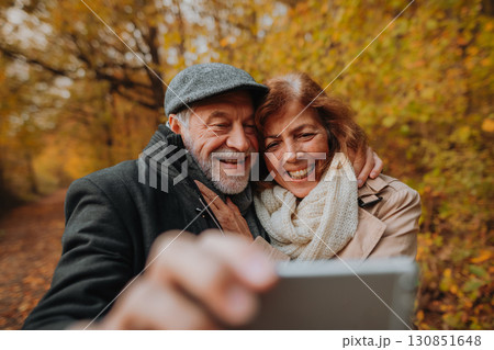 Senior man and woman taking selfie in the middle of autumn forest. Senior man and woman taking selfie in the middle of autumn forest. 130851648