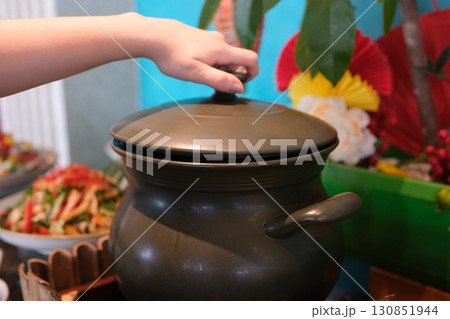 Hand touching pot reaches for the hot electric stove. Child safety at the stove.  130851944