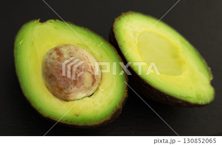Delicious ripe avocado cut in half with pit on black stone board 130852065