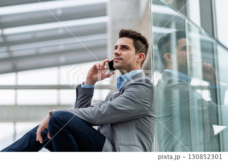 Young businessman making phone call indoors in an office. Young businessman making phone call indoors in an office. 130852301