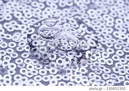 A drop of makeup on a background of silver sequins. A drop of makeup on a background of silver sequins. 130852302