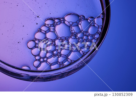 The texture of a cosmetic serum with a trail of bubbles on a purple background. The texture of a cosmetic serum with a trail of bubbles on a purple background. 130852309