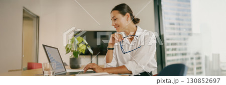 A Professional Woman Diligently Working on Her Laptop in a Contemporary Office Environment 130852697