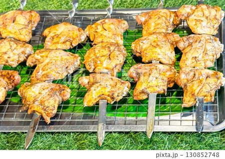Grilled chicken skewers rest on a grill, the charred lines marking their juicy perfection, an inviting sight for those seeking the simple pleasures of street food and the rustic charm of wild feasting 130852748