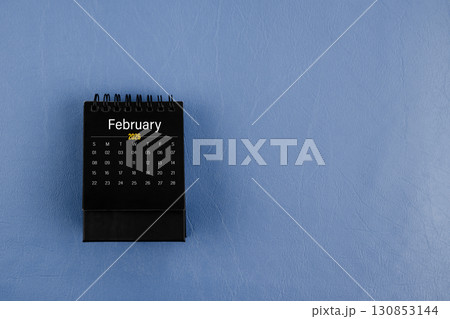 February 2026 black desk calendar on navy blue color leather background. 130853144
