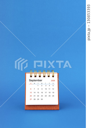 September 2026 white desk calendar on blue color background. 130853393