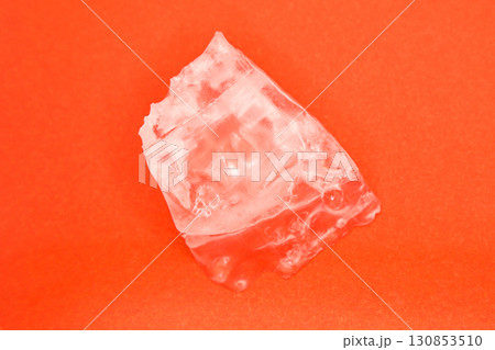 Large piece of crystal table salt on bright colored orange background, close-up 130853510