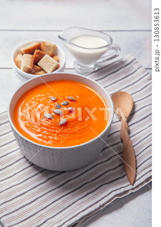 Pumpkin soup-puree with breadcrumbs, cream and seeds on towel, white wooden background Pumpkin soup-puree with breadcrumbs, cream and seeds on towel, white wooden background 130853613