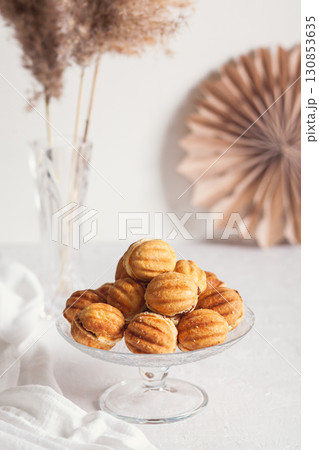 Russian traditional homemade cookies Nuts with condensed milk on glass stand on background of paper decor and reeds in vase White background, selective focus Russian traditional homemade cookies Nuts with condensed milk on glass stand on background of paper decor and reeds in vase White background, selective focus 130853635
