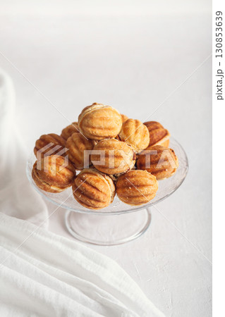 Russian traditional homemade cookies Nuts with condensed milk on a glass stand. White background, selective focus Russian traditional homemade cookies Nuts with condensed milk on a glass stand. White background, selective focus 130853639