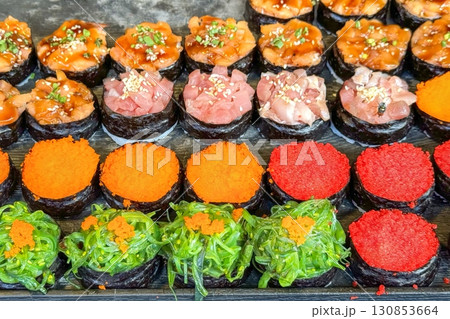 Colorful sushi selection on display, with red tobiko, green seaweed, orange masago, and chopped tuna, inviting street food lovers to enjoy authentic asian flavors 130853664