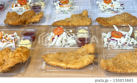 Display of Asian street food with crispy breaded steak, fresh side salads, and sauce in clear plastic containers. Concept of flavorful, tasty takeaway meals Display of Asian street food with crispy breaded steak, fresh side salads, and sauce in clear plastic containers. Concept of flavorful, tasty takeaway meals 130853665