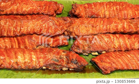 Sizzling pork belly strips on a banana leaf display the allure of Asian street food, with caramelized, crispy edges enticing with rustic charm and bold flavors Sizzling pork belly strips on a banana leaf display the allure of Asian street food, with caramelized, crispy edges enticing with rustic charm and bold flavors 130853666