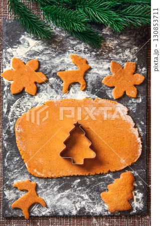 The process of making Christmas Ginger cookies. A Christmas tree-shaped mold on a raw dough for gingerbread cookies The process of making Christmas Ginger cookies. A Christmas tree-shaped mold on a raw dough for gingerbread cookies 130853711