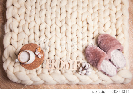 Home slippers made of fur, cup of cappuccino and inscription Home on blanket of thick yarn Home slippers made of fur, cup of cappuccino and inscription Home on blanket of thick yarn 130853816