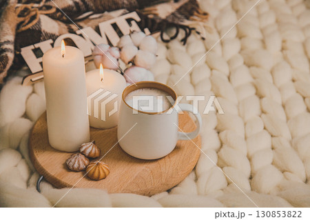 Cup of cappuccino and cookies, candles, checkered plaid, inscription Home on the background of blanket of thick yarn. Cup of cappuccino and cookies, candles, checkered plaid, inscription Home on the background of blanket of thick yarn. 130853822