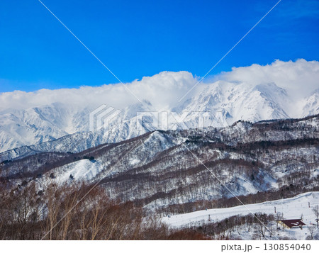 スキー場から見る雪を纏った白馬三山の壮大な冬の風景 (長野県、白馬、栂池高原) 130854040