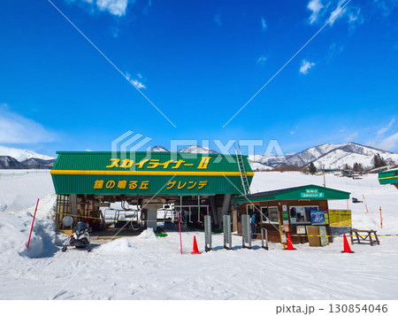 青空のスキー場とリフト乗り場、遠くに雪山を望む風景 (長野県、白馬、栂池高原) 130854046