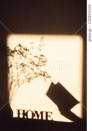 Shadow on wall with inscription Home, dried bouquet and an open book in woman's hand Shadow on wall with inscription Home, dried bouquet and an open book in woman's hand 130854104