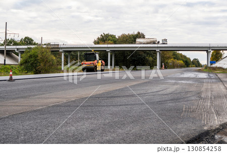 Road roller working on asphalt pavement near highway bridge during road construction 130854258