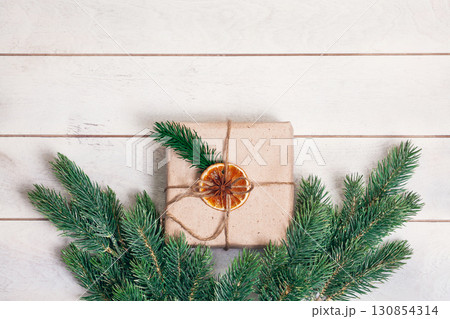 Gift boxed in eco friendly style: natural rough paper, rope of jute, spruce twigs on white wooden background Gift boxed in eco friendly style: natural rough paper, rope of jute, spruce twigs on white wooden background 130854314