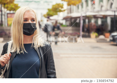 Woman in a black protective mask against background of the city 130854792