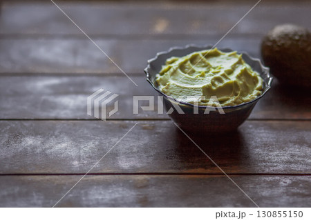 Traditional latinamerican mexican sauce guacamole in bowl and avocado on dark background with copy space 130855150