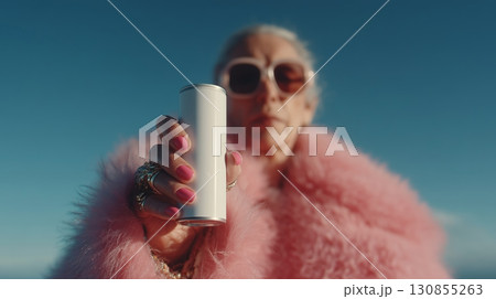 A cool grandma holding a tall soda can up to the camera.  130855263