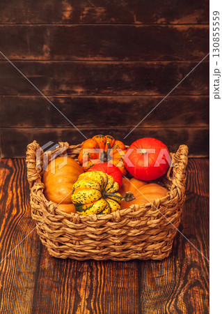 Basket with different varieties of pumpkin on a wooden background Basket with different varieties of pumpkin on a wooden background 130855559