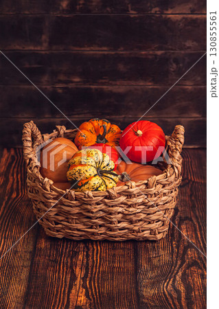 Basket with different varieties of pumpkin on a wooden background Basket with different varieties of pumpkin on a wooden background 130855561