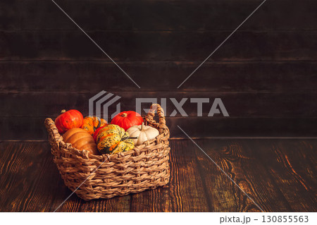 Basket with different varieties of pumpkin on a wooden background 130855563