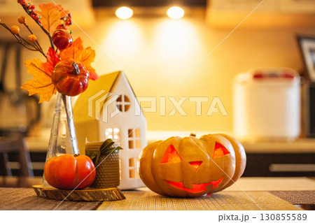 Kitchen decoration for Halloween: luminous cardboard house, candle, autumn leaves, jack-o-lantern Kitchen decoration for Halloween: luminous cardboard house, candle, autumn leaves, jack-o-lantern 130855589
