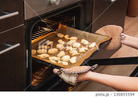 Woman opens the oven where cookies are baked for Halloween 130855594