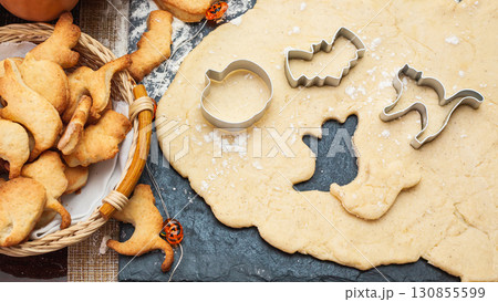 Making cookies for Halloween. Cut out cookies from dough in the form of pumpkin, cat, ghost and bat Making cookies for Halloween. Cut out cookies from dough in the form of pumpkin, cat, ghost and bat 130855599