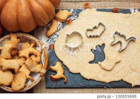 Making cookies for Halloween. Cut out cookies from dough in the form of pumpkin, cat, ghost and bat Making cookies for Halloween. Cut out cookies from dough in the form of pumpkin, cat, ghost and bat 130855600