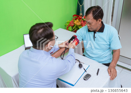 A medical professional is taking the blood pressure of a patient in a clinic setting 130855643