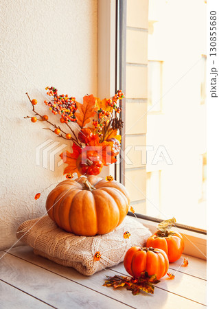 Cozy autumn still life on the windowsill: pumpkin, warm wool sweaters, ,maple leaves and persimmon 130855680