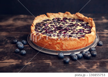 Rustic shortbread pie with blueberries in sour cream filling on a wooden background. Rustic shortbread pie with blueberries in sour cream filling on a wooden background. 130855753